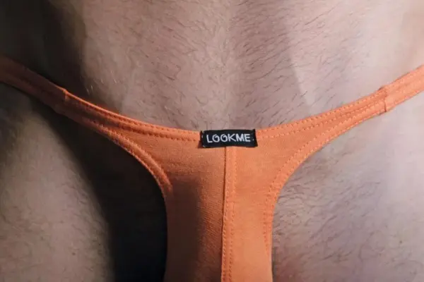 String masculin orange ajustable, vue de près, en coton élasthanne, étiquette noire visible, design sexy et minimaliste.