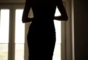 Silhouette féminine dans une robe noire ajustée, lumière du matin