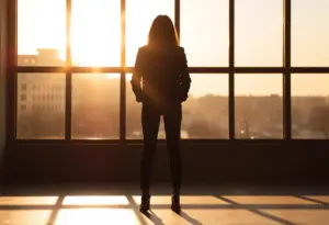 Un profil silhouetté devant une grande fenêtre au crépuscule, représentant assurance et attrait.